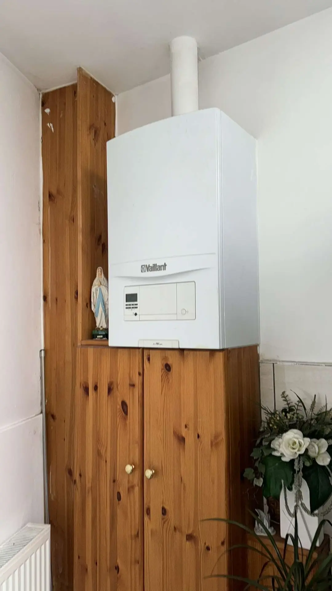 Chaudière murale gaz Vaillant installée dans une niche en bois avec évacuation verticale en PVC — solution de chauffage central intégrée dans un intérieur domestique.